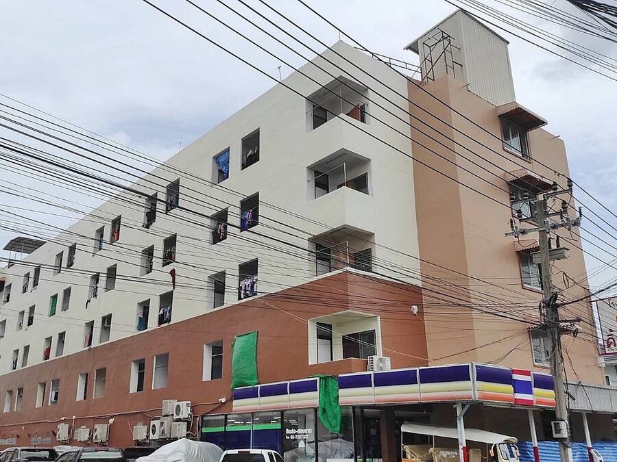 Un edificio de varios pisos con fachada plana, varias ventanas y equipos de aire acondicionado adheridos al exterior.