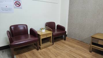 Una habitación con dos sillones de cuero, una mesita de madera con un florero y una mesita de noche de madera.