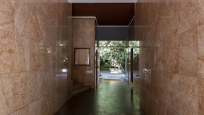 Um corredor com paredes de mármore e uma porta de vidro que dá para uma área externa.
