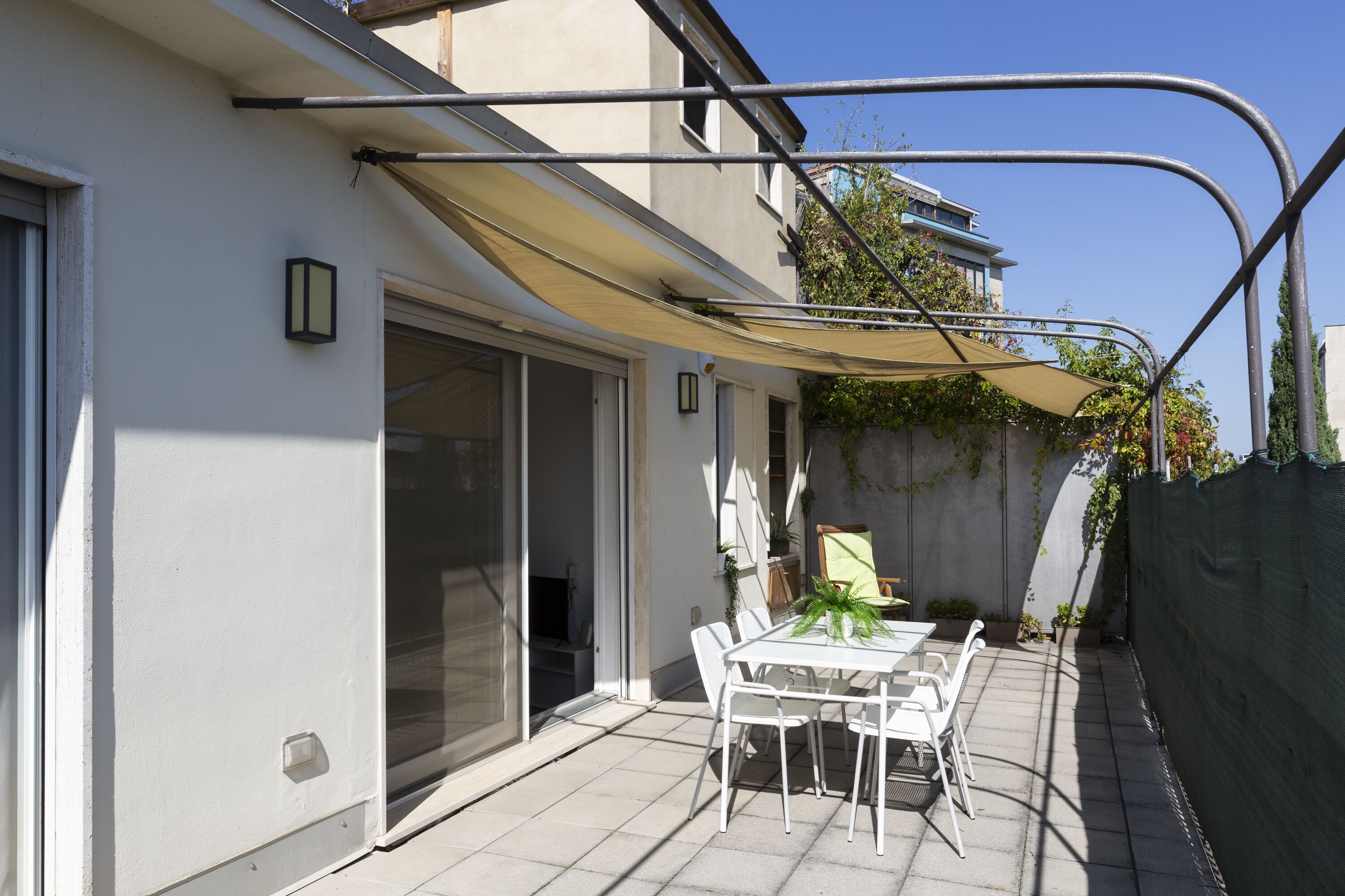 A patio with a table and chairs, a sliding glass door, and a covered area with a canopy.