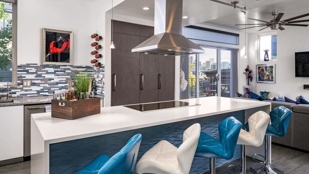 Una cocina moderna con una isla central, taburetes de bar y vistas a la ciudad.