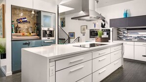 Una cocina moderna con armarios blancos, una isla grande y una campana extractora de acero inoxidable.