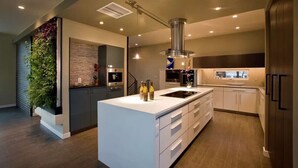 Una cocina moderna con una isla central, electrodomésticos integrados y un jardín vertical.
