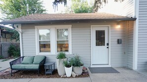 Ein Haus mit Veranda, einem grünen Sofa im Freien und drei großen Pflanzgefäßen mit Pflanzen.