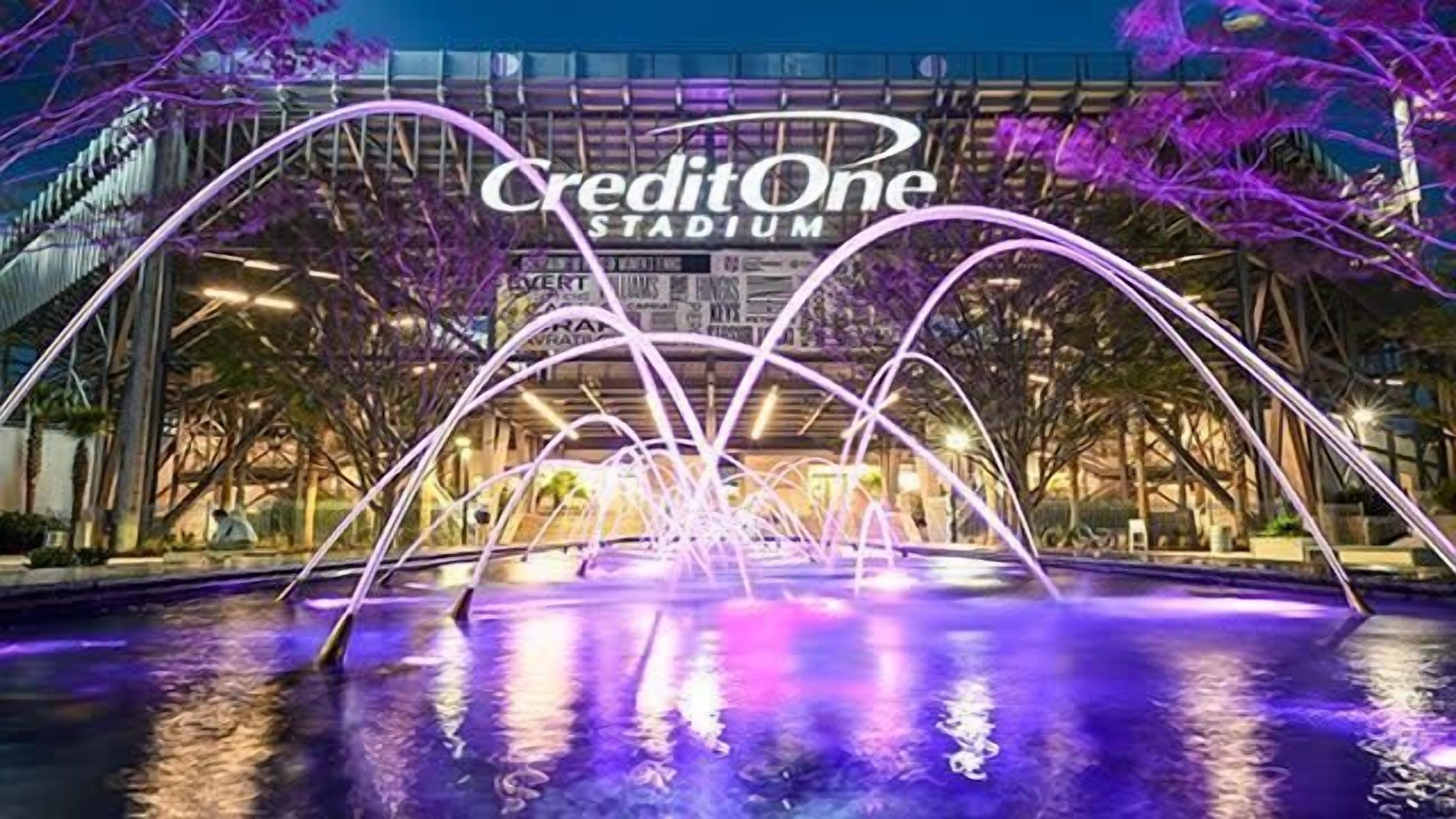 La façade extérieure du CreditOne Stadium, avec ses arches illuminées surplombant un élément décoratif aquatique.