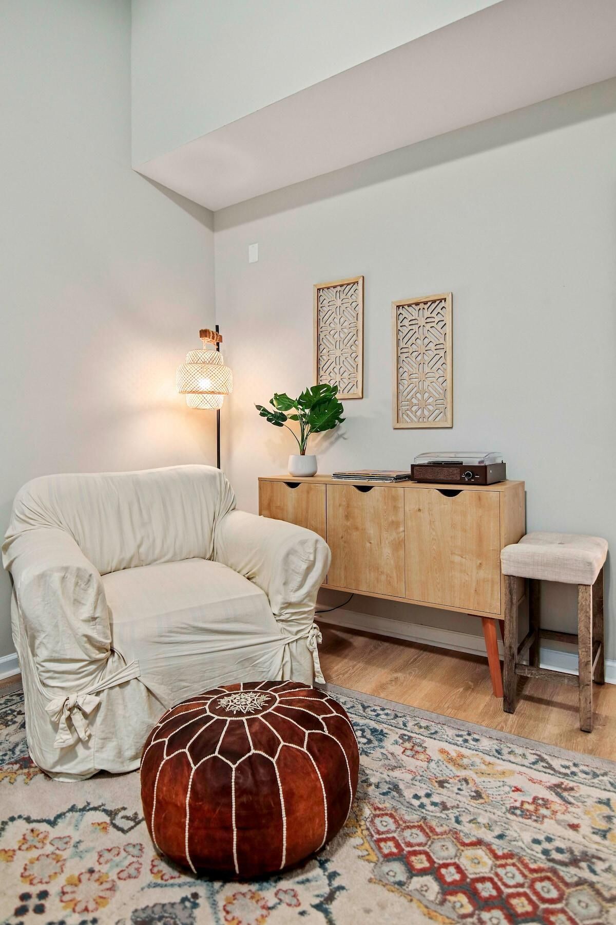 A living room with a sofa, ottoman, wooden cabinet, and a floor lamp.