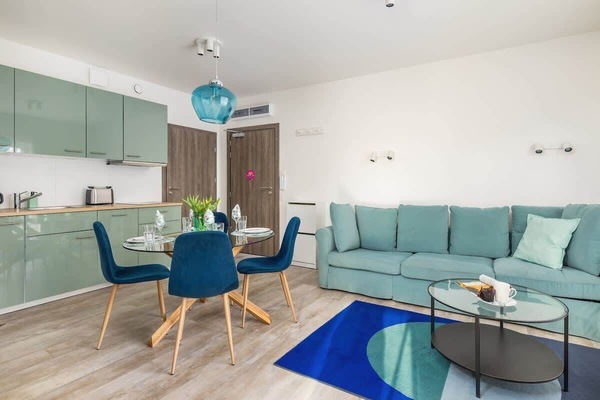 A bright living room with a mint green sofa, blue coffee table, and modern decor.