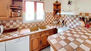 Una cocina con baldosas de cuadros, armarios de madera, lavavajillas, un lavabo, un tostador y una cafetera.