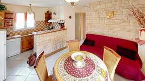 Una cocina con salpicadero a cuadros, una mesa de comedor con mantel estampado y un sofá rojo.