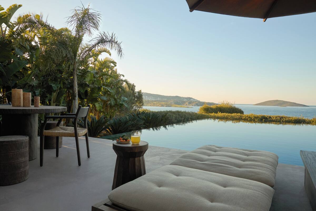 A luxurious outdoor seating area with a view of a calm body of water and distant hills.