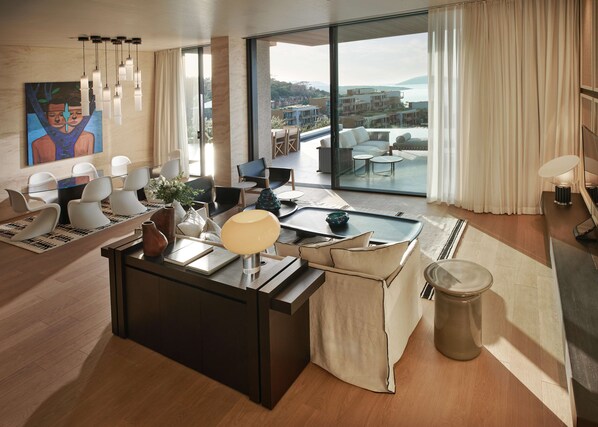 A modern living room with a glass dining area, a large painting on the wall, and a view of the cityscape. - Maxx Royal Bodrum  (Bodrum)