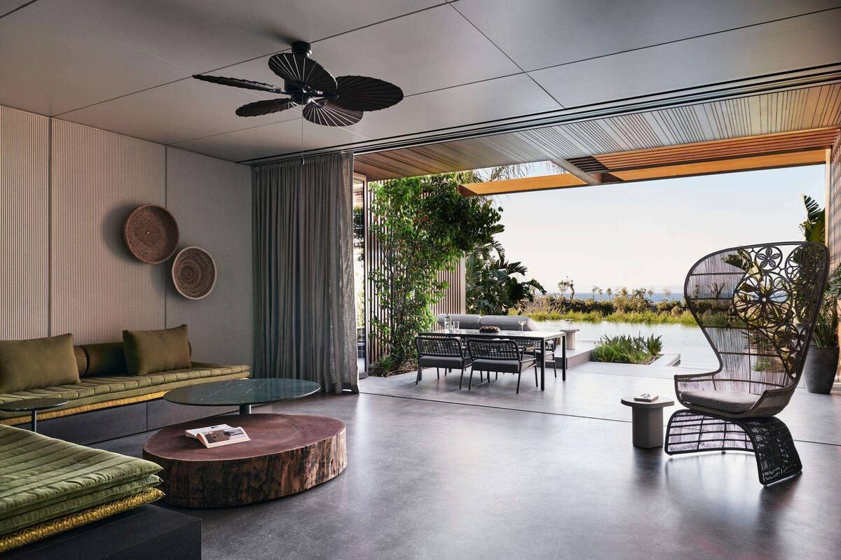 A modern living room with a sofa, a round coffee table, and a dining area with chairs and a table.