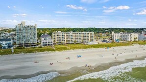 Ein Hotel direkt am Strand mit mehreren Gebäuden, einem Sandstrand und Wellen.
