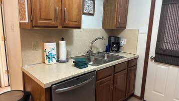 A kitchen with wooden cabinets, a stainless steel sink, a coffee maker, and a dishwasher.