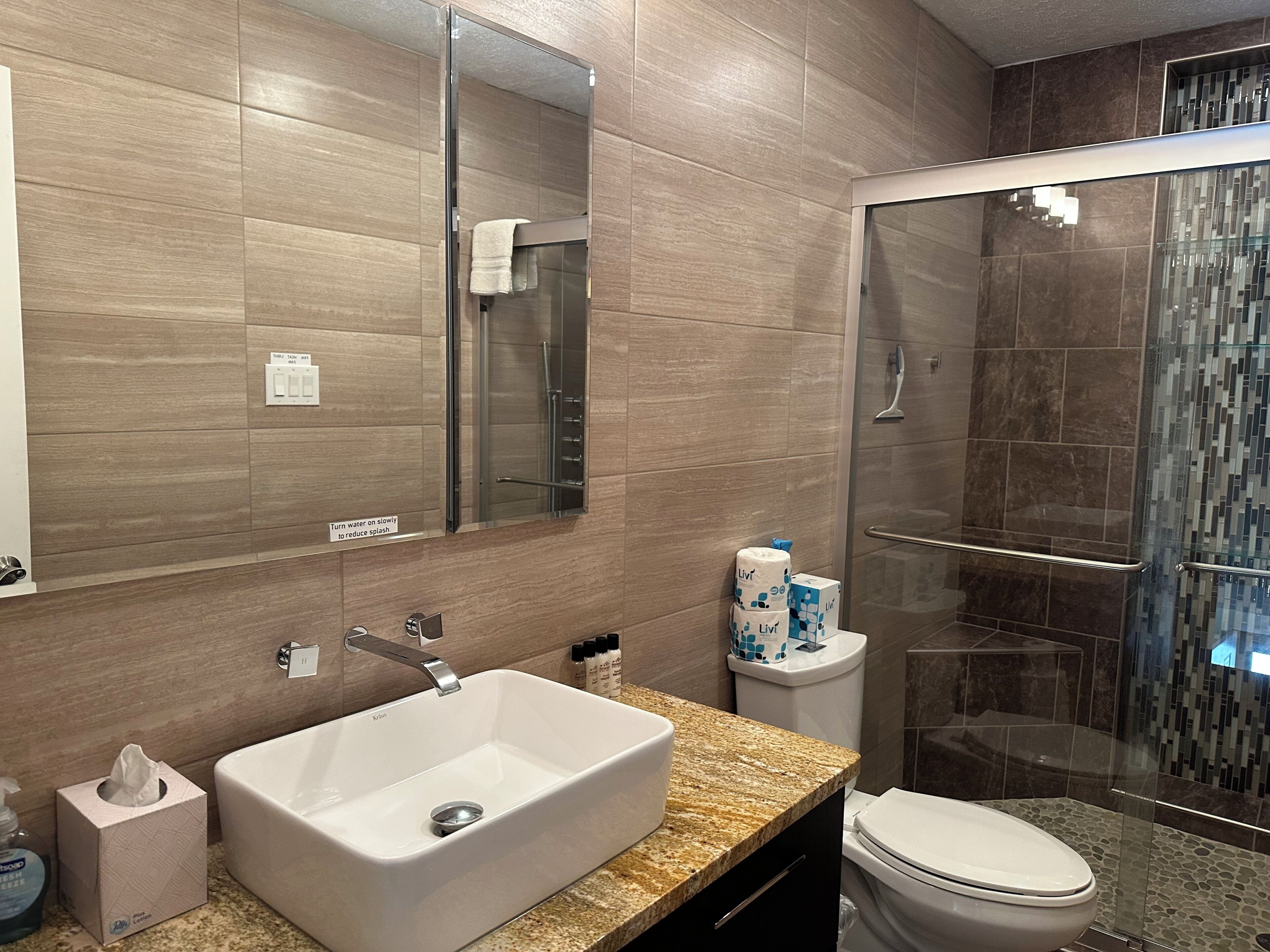 A modern bathroom with a large sink, a toilet, and a glass-enclosed shower.