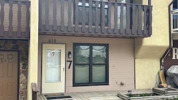 A two-story residential building with a balcony, a front door labeled '7', and a mailbox.
