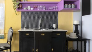 A compact kitchen with a black and white checkered floor, a purple shelf above the counter, and a black cabinet with gold handles. - Eclectic1BR in Talpiot mkt by Sea N Rent (Haifa)