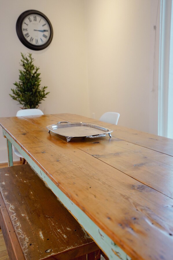 A wooden table with a tray, a clock, and a small plant on the wall.
