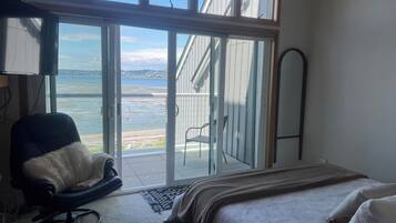 Ein Schlafzimmer mit Bett, Sessel, großem Fenster und Meerblick.