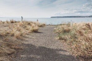 A gravel path leading to a body of water with grassy banks and a distant landmass.