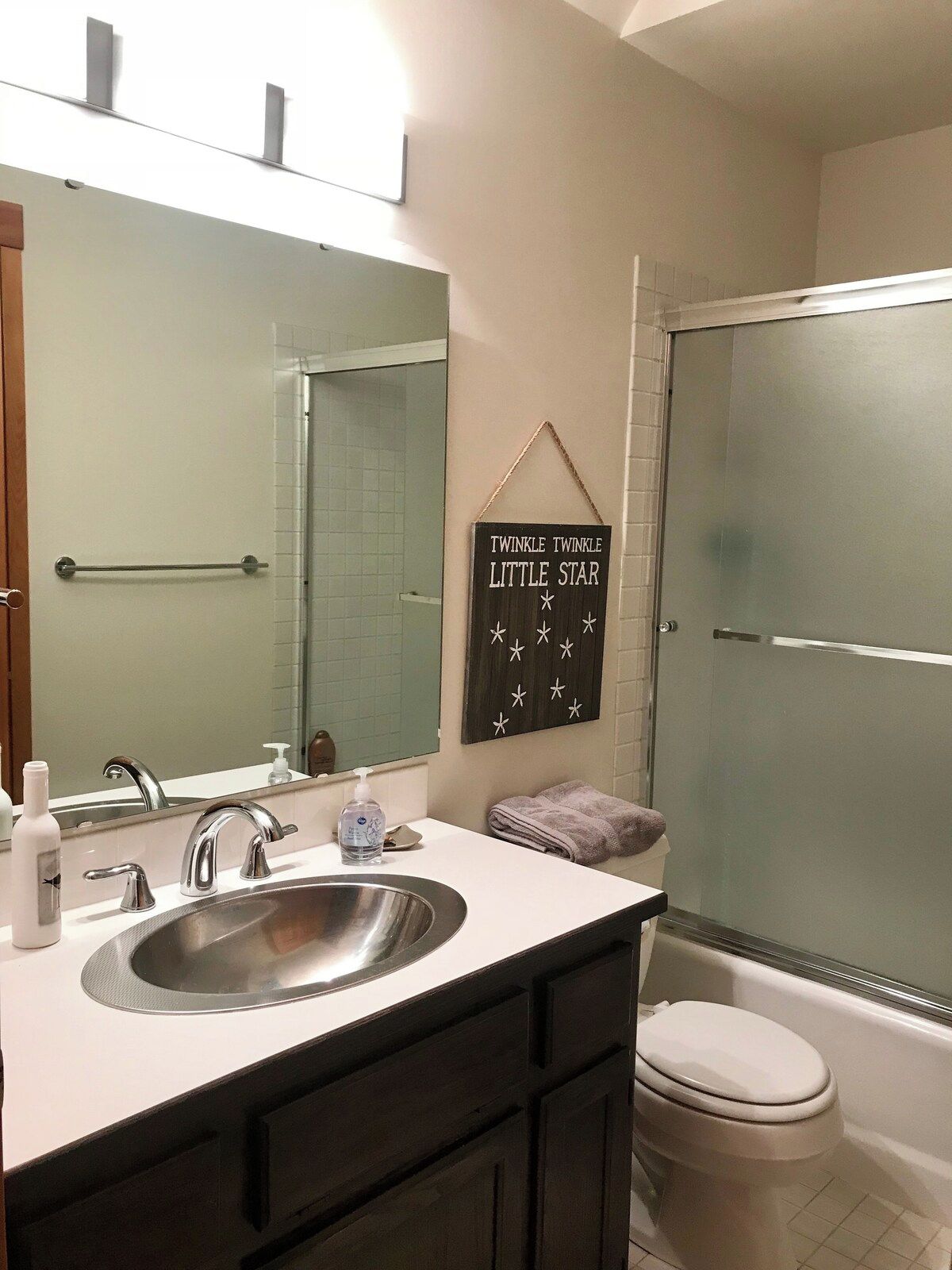 A bathroom with a sink, mirror, towel rack, and a sign that reads 'TWINKLE TWINKLE LITTLE STAR'.