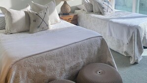 Une chambre avec deux lits, un miroir, une lampe et une grande fenêtre.