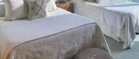 Quarto com duas camas, espelho, abajur e uma janela grande.