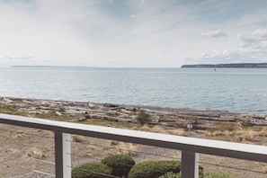 Une vue sur une étendue d’eau calme, avec une rive lointaine, une jetée en bois et un ciel dégagé.