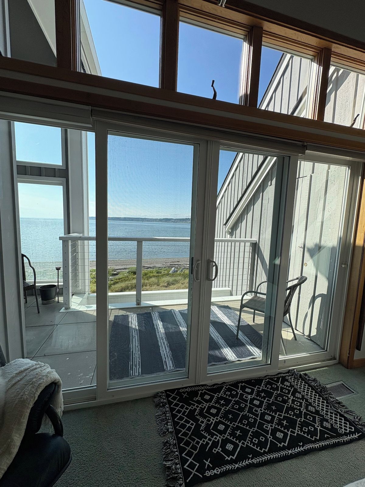 Ein Zimmer mit einer Glastür, die auf einen Balkon mit Meerblick führt.