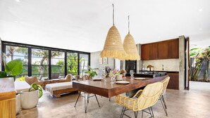A spacious kitchen with a large island, wicker chairs, and hanging rattan light fixtures. - Ohana Bungalow by Betterplace  (Canggu)
