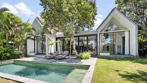 A modern house with a swimming pool, outdoor seating, and lush greenery. - Ohana Bungalow by Betterplace  (Canggu)