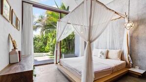 A spacious bedroom with a large bed, a canopy, and a view of lush greenery outside. - Ohana Bungalow by Betterplace  (Canggu)