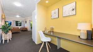 A modern living room with a sofa, a dining area with a table and chairs, and a kitchen counter with a lamp.