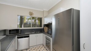 A compact kitchen with a stainless steel refrigerator, a microwave, and a dishwasher.