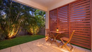 Un patio al aire libre con una mesa y sillas, una cerca de madera y palmeras.