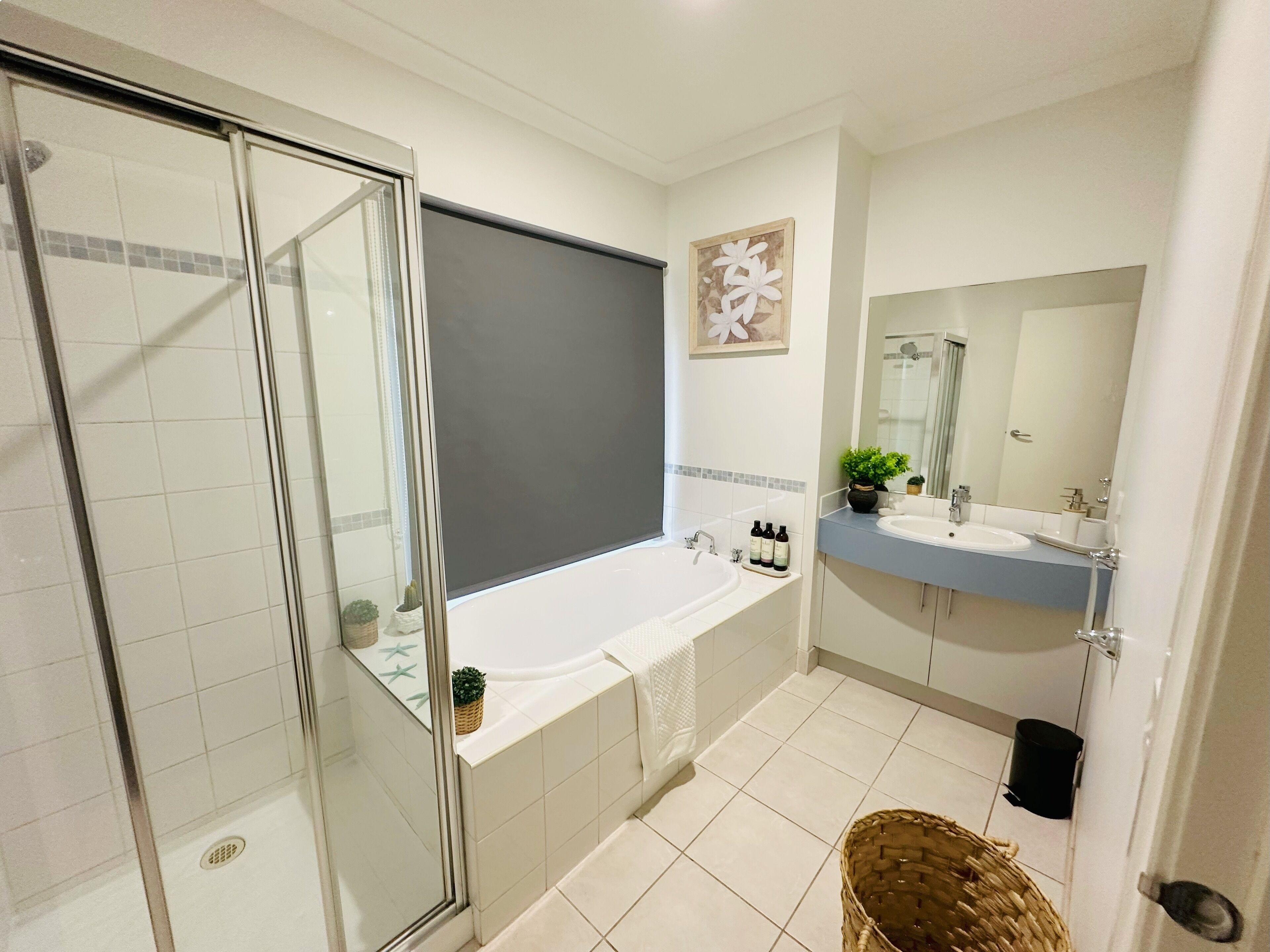 A modern bathroom with a glass shower enclosure, a large bathtub, a double sink vanity, and a mirror.