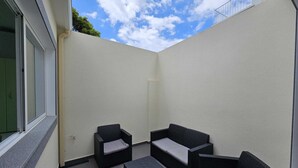 Un pequeño patio al aire libre con mobiliario de mimbre y vistas al cielo.