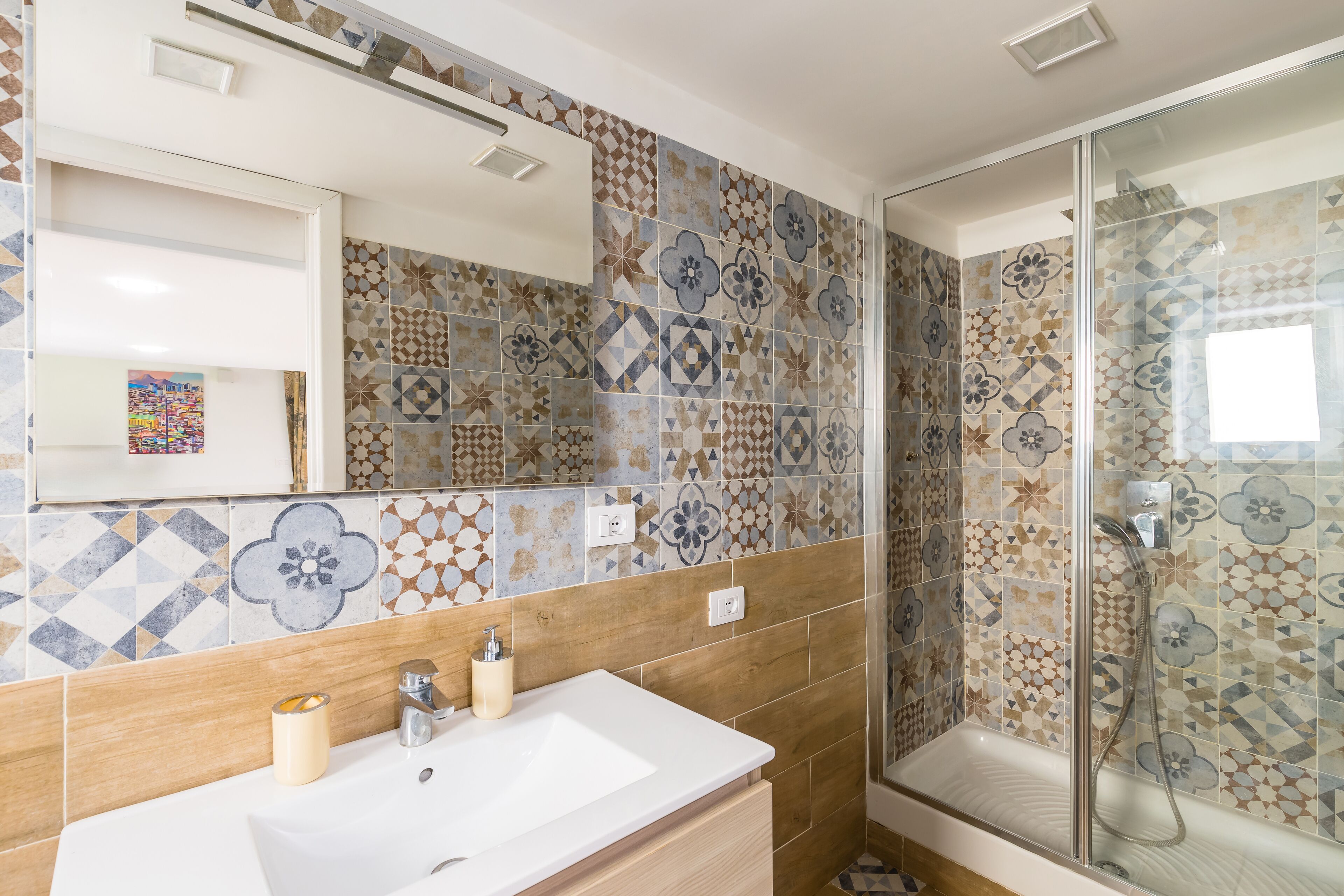 A bathroom with a sink, mirror, and shower.