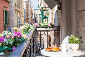 A balcony with flowers, a table with pastries, and a potted plant. - Toledo house Apartments (Naples)