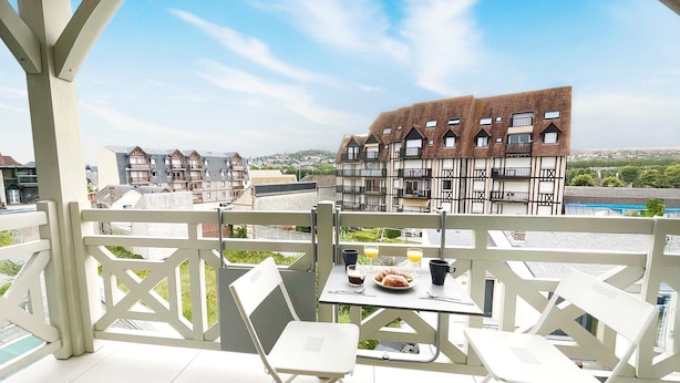 A terrace with white chairs and a table, overlooking a town with traditional buildings. - Standing, Centre, 2 Sdb 2 WC, Balcon, Parking (Deauville)