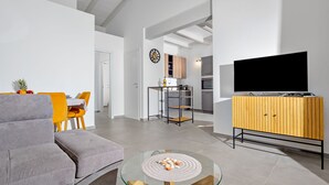 A modern living room with a grey sofa, a glass coffee table, and a TV on a wooden cabinet. - Villa Maria – brand new villa with a garden in Valledoria (Valledoria)