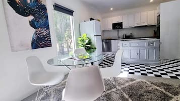 Enjoy a compact living space with a glass dining table and a vibrant abstract painting, offering a view of the outdoors.