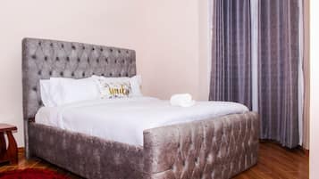 A bed with a tufted headboard, white bedding, and a rolled towel.