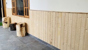 A building exterior with a wooden window, a tiled floor, and three wooden stumps. - The Kuber Hotel & Restaurant (Puh)