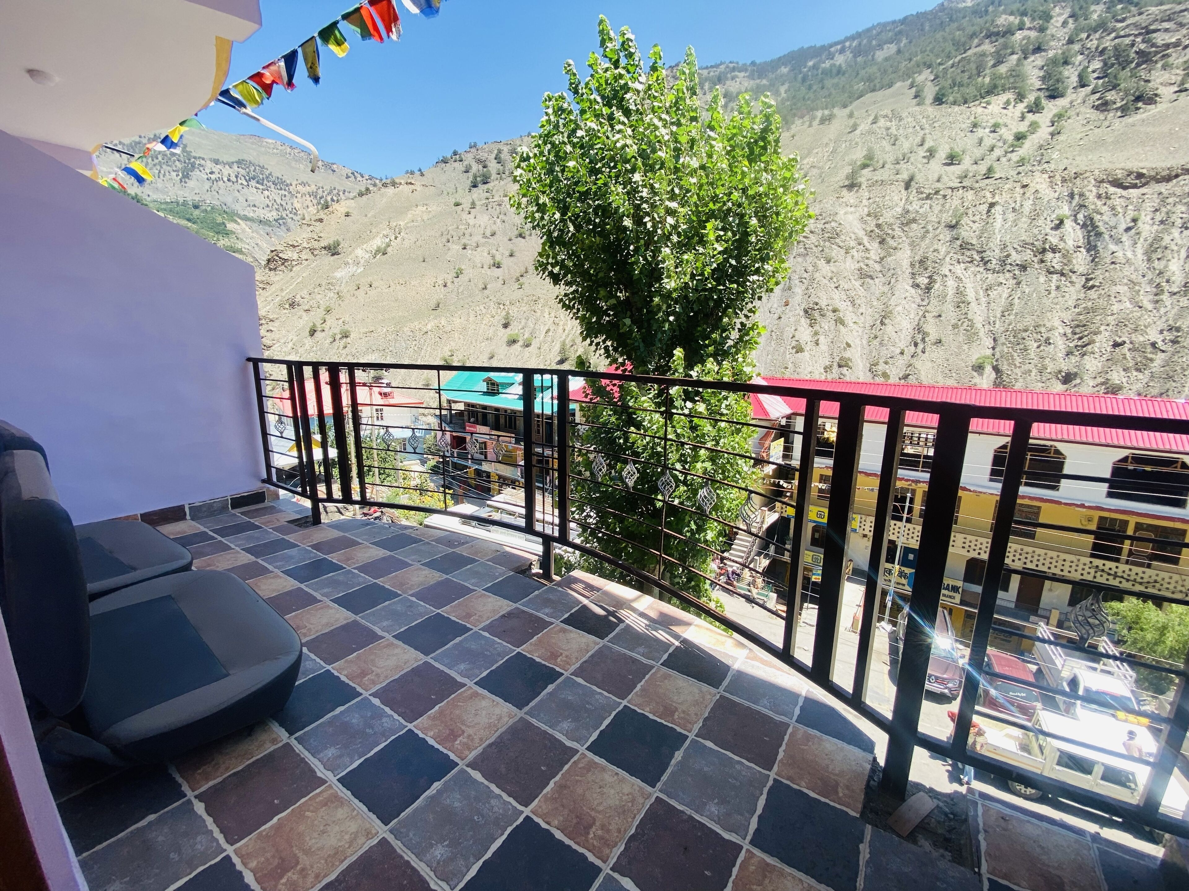 A balcony with a tiled floor, a metal railing, and a view of a mountainous landscape.
