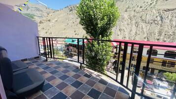 A balcony with a tiled floor, a metal railing, and a view of a mountainous landscape.