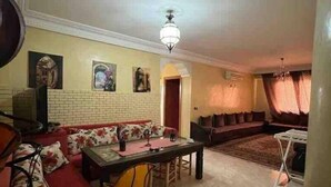A living room with a sofa, a dining table, and a TV. - Superbe Appartment en Résidence Avec Piscine (Marrakech)