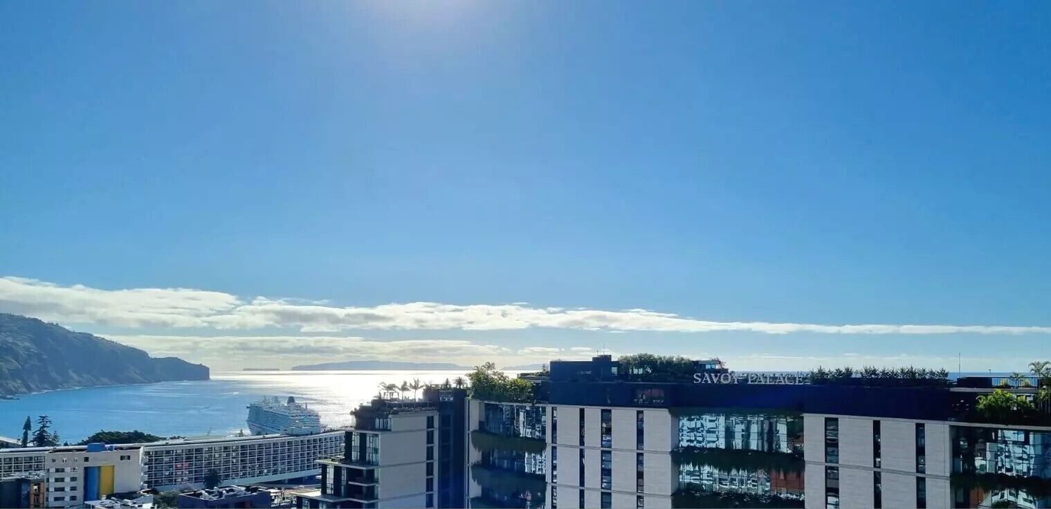 A coastal hotel with modern architecture, a pool, and a view of the sea.