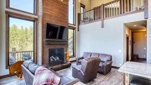 Ein geräumiges Wohnzimmer mit Kamin, Ledersofas und einer hohen Decke mit Balkon.