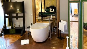 Een ruime badkamer met een vrijstaand bad, een houten wastafelmeubel en een grote spiegel.